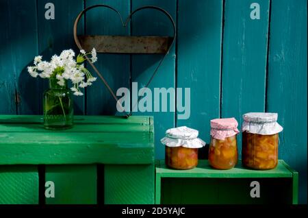 Drei Gläser von hausgemachte Rhabarber Aprikose Marmelade, herzförmigen Cutter und blühenden Waldmeister Stockfoto