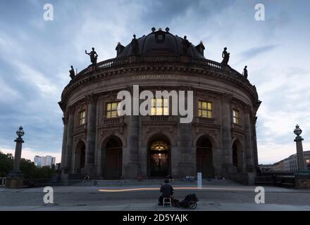 Deutschland, Berlin, Blick auf beleuchtetes Bode Museum auf der Museumsinsel mit Straßenmusiker im Vordergrund Stockfoto