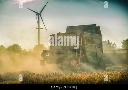 Deutschland, Grevenbroich, Mähdrescher auf Feld und Wind turbine Stockfoto