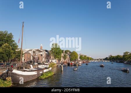 Niederlande, Grafschaft von Holland, Amsterdam, Magere Brug, Fluss Amstel mit Booten Stockfoto