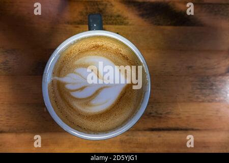 Blick von oben auf Coffee Latte mit kunstvoller Blumenform Ein Holzhintergrund Stockfoto