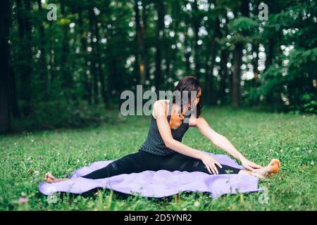 Junge Frau, die sich in der Natur ausdehnt, Yoga in der Natur Stockfoto