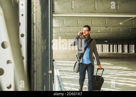 Junger Geschäftsmann zu Fuß im Parkhaus reden über Handy Stockfoto
