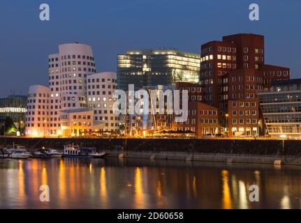 Deutschland, Düsseldorf, beleuchtete Gehry-Gebäude mit Medienhafen am Abend Stockfoto