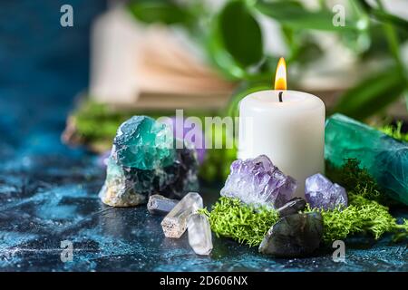 Kristalline Mineralien für Meditation, Kerze, Moos, Buch. Magic Rock für die Heilung von Steinen. Stockfoto