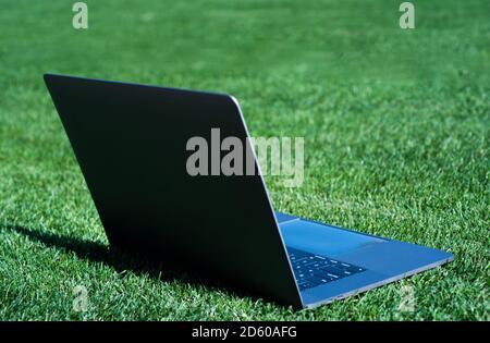 Laptop auf grünem Gras. Agiles Geschäft. Fernlernkonzept. Immer online verfügbar. Arbeiten im Frischluftpark. Computer auf Rasen. Modernes Notebook-Gerät. Digitale Umgebung. Freiberuflich. Stockfoto