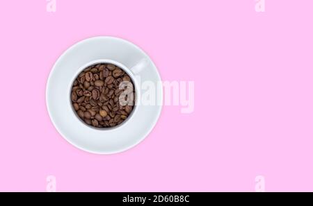 Weiße Tasse und Untertasse, volle Tasse Kaffeebohnen. Draufsicht, rosa Hintergrund. Freier Speicherplatz für Text. Stockfoto