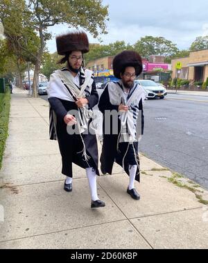 Zwei religiöse orthodoxe jüdische Männer gehen zur Synagoge auf Rosh Hashanah, dem jüdischen Neujahr entlang der McDonald Avenue in Brooklyn, New York. Es ist auffällig, dass sie keine Gesichtsmasken tragen, obwohl es während der Covid-19 Pandemie ist. Stockfoto