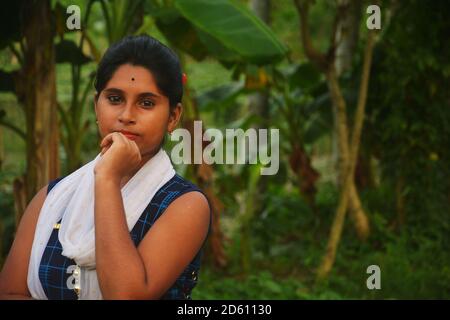 Nahaufnahme eines indischen bengalischen Teenage-Mädchens in blauem Salwar und weißer Dhuppata, das mit der linken Hand auf dem Mund steht und selektiv fokussiert Stockfoto