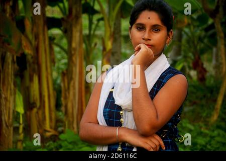 Nahaufnahme eines indischen bengalischen Teenage-Mädchens in blauem Salwar und weißer Dhuppata, das mit der linken Hand auf dem Mund steht und selektiv fokussiert Stockfoto