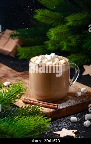 Heißer Weihnachtsdrink. Kakao Kaffee oder Schokolade in Gläsern mit Marshmallows und Siebe Puderzucker auf dunklem Hintergrund. Stockfoto