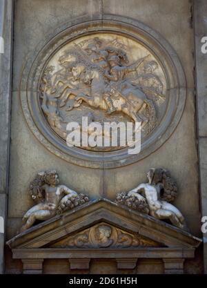 Spanien, Andalusien, Granada. Palast von Karl V. Der Bau wurde von Kaiser Karl V. wegen der Notwendigkeit eines Ortes, der alle Annehmlichkeiten der Zeit für den Kaiser und seine Familie erfüllt bestellt. Der Architekt Pedro Machuca (ca. 1490-1550) begann die Arbeiten im Jahr 1527. Juan de Herrera entwarf die Hauptabdeckung an dieser Fassade (Westseite) und modifizierte Machuca's Plan. Detail eines der Medaillons, der einen Kavallerieanschlag darstellt, der von Antonio de Leval (1558-1561) modelliert wurde. Stockfoto