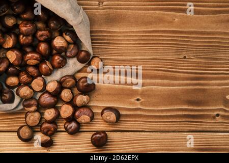 Vertikale Aufnahme von Kastanie in der Leinentasche auf einem Holztisch Stockfoto