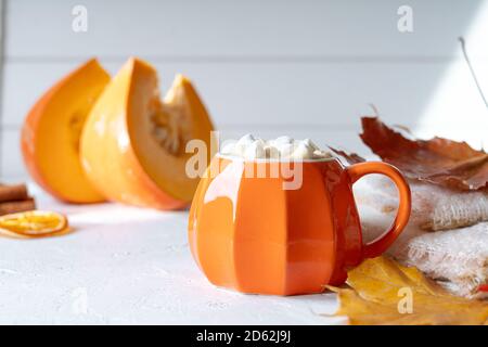 Komposition mit orangefarbenem Kürbis-Stil Tasse Kaffee mit Marshmallows und Herbstdeko, gefallenen Blättern, gemütlichem Pullover auf weißem Hintergrund. Stockfoto