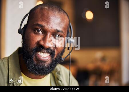 Gutaussehender afroamerikanischer Mann in Kopfhörern, der positive Emotionen ausdrückt Stockfoto