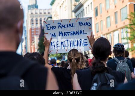 Menschenmenge von Demonstranten mit Schildern, "Ende der Rassenabwägen in der mütterlichen Gesundheitsversorgung", während des Juneteenth March, New York City, New York, USA Stockfoto