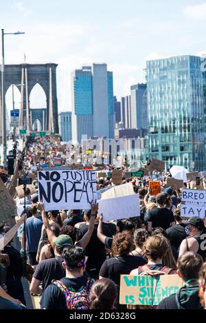 Massen von Demonstranten mit Schildern, die über die Brooklyn Bridge marschieren während des 6. März, New York City, New York, USA Stockfoto