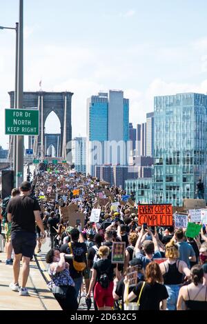 Massen von Demonstranten mit Schildern, die über die Brooklyn Bridge marschieren während des 6. März, New York City, New York, USA Stockfoto