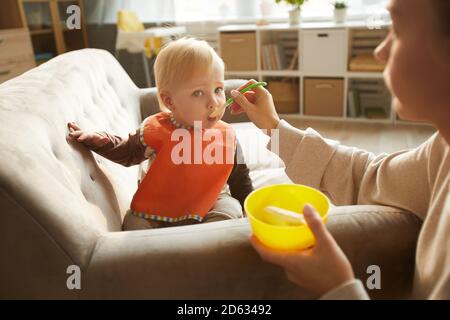 Baby Junge essen mit Hilfe seiner Mutter während Mittagspause zu Hause Stockfoto