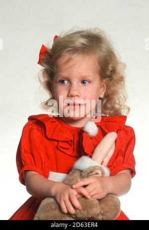 Niedliches blondes Mädchen Kleinkind hält ein Stofftier an Weihnachten, USA Stockfoto