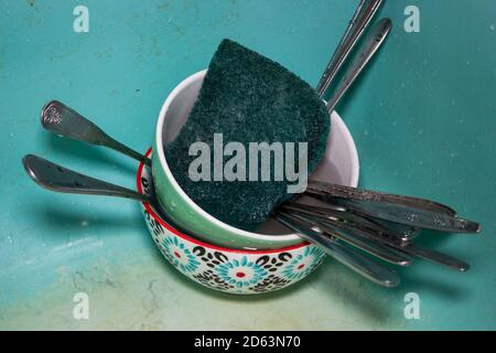Schmutziges Geschirr mit Löffeln und Schwamm im Waschbecken Stockfoto