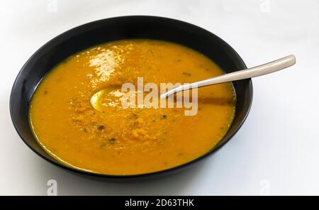 Karotten- und Koriandersuppe in einer schwarzen Schüssel Stockfoto