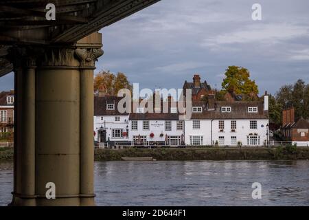 The Bull's Head, historisches Pub am Strand on the Green, Kew, West London. Fotografiert von der anderen Seite der Themse. Kew Railway Bridge im Vordergrund Stockfoto