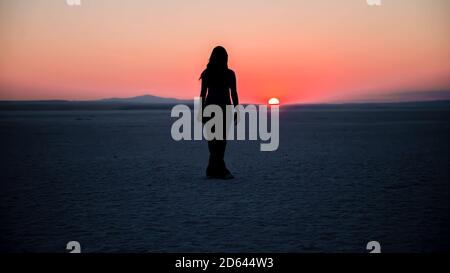 Ankara, Türkei - August 2013: Silhouette einer unbekannten Frau, die den Sonnenuntergang am Tuz Golu See in Ankara, Türkei, beobachtet Stockfoto