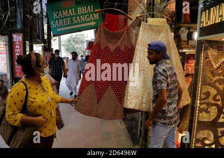 Neu Delhi, Indien. Oktober 2020. Eine Frau, die eine Gesichtsmaske trägt, schaut auf ein Hochzeitskleid (Lehenga), das außerhalb des Shops ausgestellt ist.in Indien wurden an einem einzigen Tag mehr als 63,509 Fälle von Coronavirus gemeldet, und 7,239,389 bestätigte Fälle von Covid-19 mit 110, 586 Todesfällen. Kredit: Naveen Sharma/SOPA Images/ZUMA Wire/Alamy Live Nachrichten Stockfoto