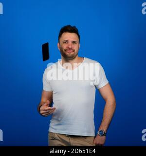 Hübscher junger Mann in eleganter Freizeitkleidung mit Smartphone Und mit einem Lächeln auf die Kamera schauen Stockfoto