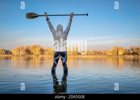 Silhouette eines männlichen Stand Up Paddlers beim Aufwärmen und Dehnen, Herbstlandschaft eines Sees im Norden Colorados Stockfoto