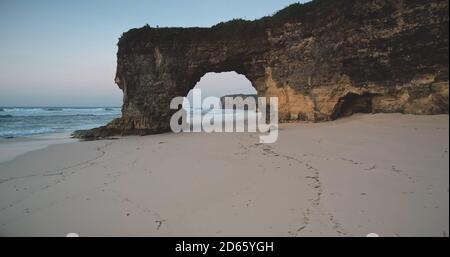 Einzigartige geologische Formation von Batu Bolong - riesiges Loch in Felswand am Sandstrand, Meeresbucht Luftaufnahme. Felsenküste von Bawana Beach, Sumba Island, Indonesien, Asien. Touristische Wahrzeichen Drohne erschossen Stockfoto