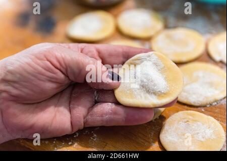 Kleine Krümel aus rohem Teig mit Mehl auf einem bedeckt Schneidbrett aus Holz Stockfoto