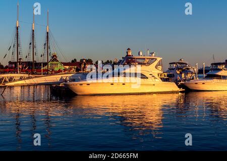 Die Boote dockten bei Sonnenuntergang am Rainbow Harbour im Shoreline Village an, mit Restaurants und Geschäften im Hintergrund. Stockfoto