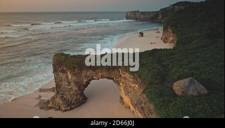 Indonesien Wahrzeichen Nahaufnahme Luftaufnahme: Riesiges Loch auf Klippenwand von Batu Bolong, Bawana Beach, Sumba Island. Einzigartige geologische Formation mit grünem Gras und Bau auf der Oberseite. Sommer niemand Natur Landschaft Stockfoto