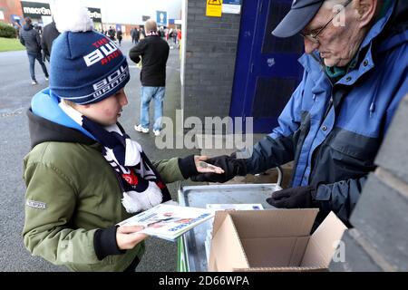 Ein junger Bolton Wanderers Fan kauft sich vor dem Spiel ein Programm Stockfoto