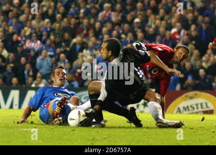 Manchester United's Rio Ferdinand und Torhüter Tim Howard kombinieren Blockieren Sie Fernando Ricksen von den Rangers Stockfoto