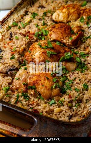 Italienische Knoblauch ohne Knochen und ohne Haut Hähnchenschenkel und brauner Reis Auflauf mit Pilzen, grünen Erbsen und geriefenen Karotten Stockfoto