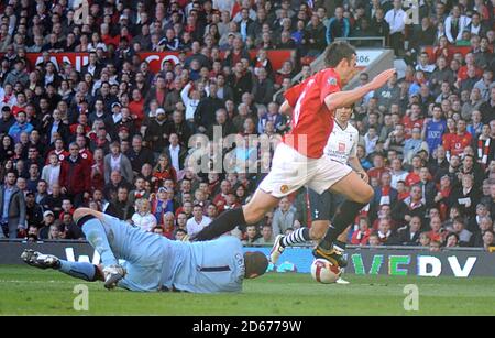 Michael Carrick von Manchester United (rechts) wird von Tottenham Hotspur-Torwart Heurelho Gomes auf den Boden gebracht, was zu einer Strafe führt. Stockfoto