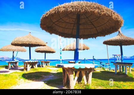 Exotische Sonnenschirme und Tische am Strand. Tropische Sommerterrasse Stockfoto