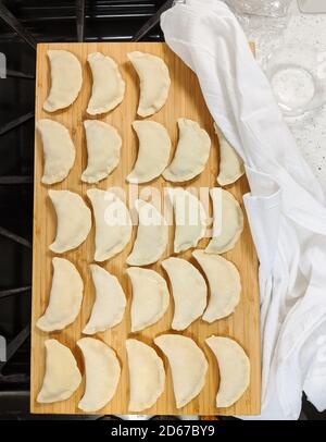 Pierogis und Teig auf einem Holzbrett mit weißer Baumwolle Tuch an der Seite Stockfoto