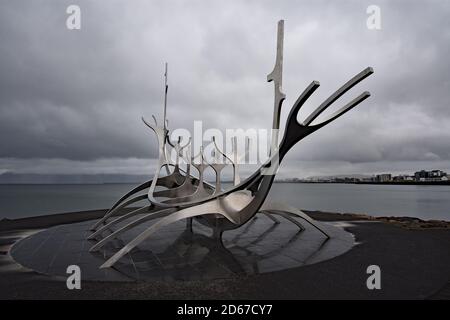 Die Sun Voyager (Sólfarið) ist eine große Stahlskulptur eines wikingerschiffs. Hinter der Skulptur ist die Bucht Faxaflói und ein Teil von reykjavik zu sehen. Stockfoto