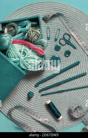Häkelnadeln zum Stricken von Wollfäden und Klebeband Messen Sie auf einer grünen texturierten Tabelle in der Ansicht von oben Stockfoto