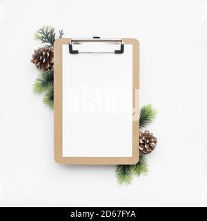 Draufsicht auf ein Klemmbrett, Tannenzweige und Tannenzapfen für Weihnachten mit Kopierraum Stockfoto