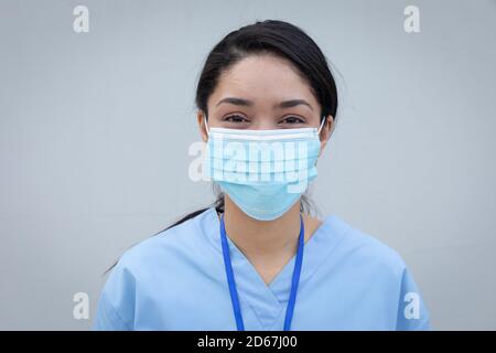 Portrait der weiblichen Gesundheitsfachkraft trägt Gesichtsmaske gegen grau Hintergrund Stockfoto