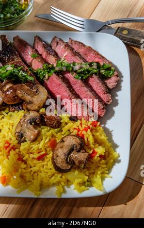 Saftige seltene Chimichurri verde gegrilltes Clubsteak mit gelbem Reis Und Pilze Stockfoto