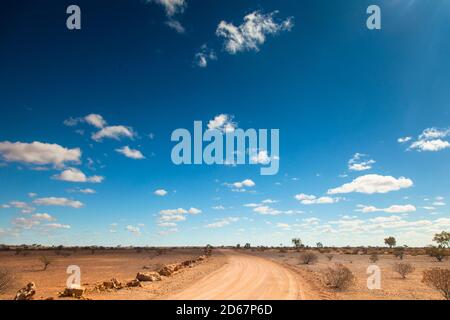 Nicht versiegelte Outback Road roten Schmutz unter einem blauen Himmel, Bladensburg National Park, Winton, Outback Queensland. Stockfoto