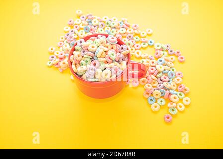 Schüssel Müsli, bunte Müsli in einer leuchtend roten Schale auf Holz, Müslischlaufen auf gelbem Hintergrund. Schnelles Frühstück oder Snack, flat Lay. Stockfoto