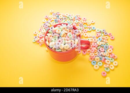 Schüssel Müsli, bunte Müsli in einer leuchtend roten Schale auf Holz, Müslischlaufen auf gelbem Hintergrund. Schnelles Frühstück oder Snack, flat Lay. Stockfoto