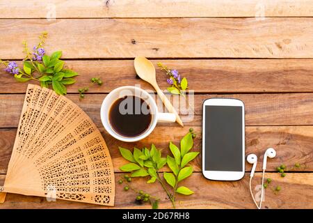 Handy, heißer Kaffee, Holzventilator und Blumen, Blattarrangement Flach Lay-Stil auf Hintergrund Holz Stockfoto